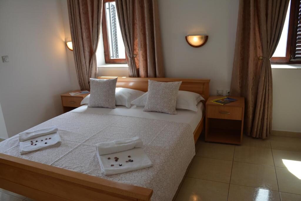 Bright bedroom with two windows, curtains and fresh towels on the bed