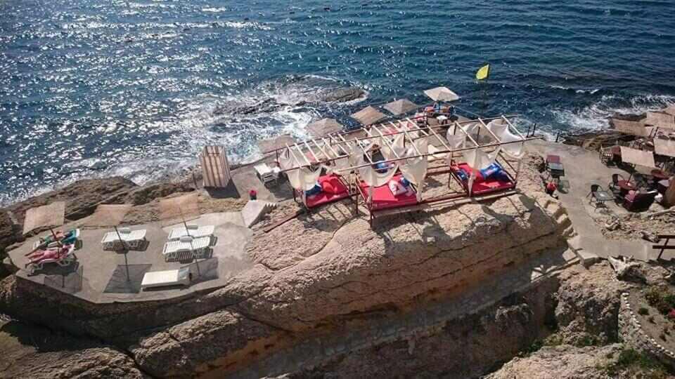 Sun beds and umbrellas on the rocks below the villa